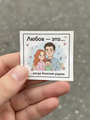 Фотография сделана крупным планом, под естественным светом. В кадре видна рука, которая держит маленький бумажный вкладыш, похожий на тот, что обычно встречается в упаковке жевательной резинки. На нем изображен рисунок, который немного помят. Основное внимание уделено именно этому вкладышу.
