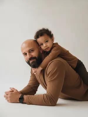 Изобрази на фотографии студийный портрет родителя и ребенка, сохраняя точные черты лиц и выражения с оригинальных снимков. Не меняй и не искажай контуры лиц, передай их с фотореалистичной точностью.