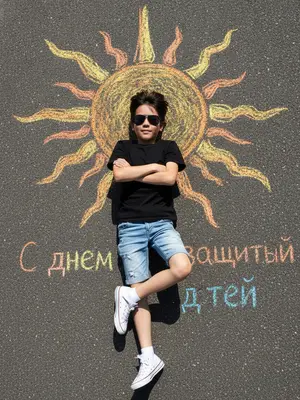 From above, a child lounges on the rough, dark asphalt. Above their head, a sun drawn in bright chalk beams with vibrant rays. The child sports black shades, a tee, denim shorts, and sneakers paired with white socks. Their arms are folded on the chest, legs crossed at the ankles. The chalk sun shimmers in yellow, orange, and golden hues. The harsh midday sunlight casts sharp shadows, creating a high-contrast scene. The atmosphere is playful and summery. On the ground, colorful chalk letters spell out "Happy Children's Day". The image is photorealistic, in 8k resolution, with intricate details.