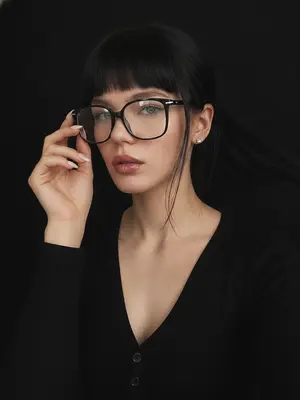 Фотография с винтажным налетом, пропитанная темным шиком в стиле dark glam glasses selfie, создает атмосферу загадочного ночного портрета. Крупный план, кадр обрезает грудь. Модель погружена в процесс селфи, телефон скрыт. Лицо занимает большую часть кадра, слегка повернуто в сторону. Голова наклонена в небольшом углу. Взгляд направлен точно в объектив, выражение спокойное, уверенное и манящее. Губы нежно раскрыты. Рука приподнята к лицу, легко касаясь оправы очков, словно корректируя их положение.

Макияж идеальный в стиле dark glam. Кожа сверкает ровным сияющим оттенком, брови четко выделены темными линиями, ресницы длинные и пышные, стрелка тонкая, контуринг мягкий. Губы окрашены в винно-розовый оттенок с блестящим влажным финишем.