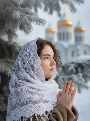 Женщина с макияжем и прической, стоит в полу профиль перед камерой. Ее лицо, не измененное, выглядит точно как на фото. Ладони сложены в мирном жесте, касаясь края белого полупрозрачного платка, который покрывает ее голову. В фоне размытый силуэт православного храма с золотыми куполами, утопающих в заснеженных крышах. Зимнее утро, лучи солнца проникают сквозь иней на ветвях ели. Детально проработаны текстуры кожи, кружева и снега, создавая атмосферу чистоты и духовности. Изображение выполнено в гиперреализме с разрешением 8k, отображая реалистичные ткани зимней одежды и хвои, покрытой инеем.