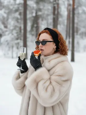 В заснеженном лесу стоит элегантная женщина в стиле "Slavic Girl", окруженная зимней красотой. На ушах блестят золотые серьги круглой формы, подчеркивающие ее образ. Она утеплена в роскошную объемную шубу из светлого меха, а под ней виден белый свитер с высоким воротником. Черная повязка на голове и стильные узкие солнцезащитные очки добавляют загадочности ее облику.

В полупрофиль она держит бокал игристого шампанского в одной руке, а другой рукой наслаждается бутербродом с красной икрой. Черные кожаные перчатки на ее руках подчеркивают изысканный стиль. Атмосфера роскоши и зимней эстетики окутывает ее, создавая впечатление изысканности и изящества.

Мягкое естественное освещение подчеркивает каждую деталь, добавляя высокое качество и реализм сцене. При этом прическа остается без изменений, сохраняя свою первозданную красоту и стиль. 
