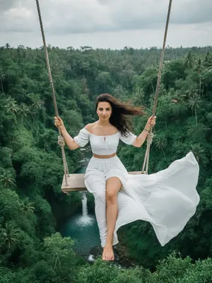 На фотографии изображена женщина в ярком платье с цветочным принтом, стоящая на песчаном пляже. Ее волосы развеваются на ветру, создавая игривые завитки вокруг ее лица. Она улыбается, демонстрируя белоснежные зубы, и ее глаза сияют радостью. В руках у нее коктейль в кокосовом стакане с цветком украшением. Фоном служит бирюзовое море и пальмы, создающие тень на песке. Вся сцена наполнена яркими красками и атмосферой летнего праздника. 