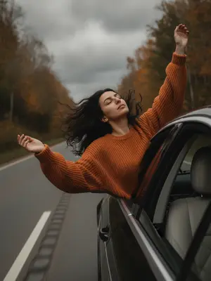Ветер нежно играет с локонами, которые свободно развиваются на фоне движения машины. На губах девушки легкий оттенок пыльной розы, а ее кожа выглядит слегка загорелой. Сцена запечатлена в момент, когда она высовывается из открытого окна автомобиля ярко-желтого цвета. Камера расположена снаружи, немного сбоку и сзади, показывая, как машина занимает правую часть кадра, а слева уходит вдалеке пустая дорога. Женщина, облокотившись на край окна, почти полностью выдвинула верхнюю часть тела наружу. Ее руки грациозно подняты, локти выпрямлены. Тело слегка наклонено назад, грудная клетка раскрыта, шея вытянута, а голова откинута. Глаза закрыты, а ветер треплет волосы и слегка колышет ткань ее свитера. 

На ней оранжевый объемный вязаный свитер oversize с длинными свободными рукавами, который почти полностью скрывает нижнюю часть ее тела. Вокруг расстилается живописный осенний лес, а над ним нависает тяжелое серое небо, местами видимое сквозь листву. Вся обстановка передает атмосферу прохладной осени, предвещая дождь. 