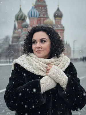 На фотографии изображен портрет груди девушки. Она одета в черную шубу, а плечи, голова и грудь украшены светлым кружевным мохеровым шарфом. Также на ней надеты варежки из того же материала. Одна рука девушки ласкает другую, а их ладони переплетены и покоятся на груди. Лицо девушки, обращенное к камере, украшает легкая задумчивая улыбка, а ее глаза смотрят влево. Густо накрашенные ресницы придают ей загадочный вид. На заднем плане зимний пейзаж с собором Василия Блаженного в Москве, покрытым снегом. Фон сильно размыт, словно под воздействием снегопада. Вся сцена пронизана легким холодным эффектом и зернистостью, что создает атмосферу зимнего волшебства. 
