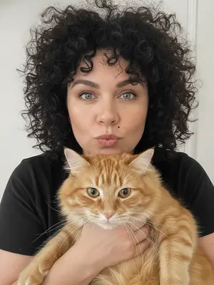 Создайте изображение, на котором девушка улыбается в камеру, держа в руках смартфон. Ее глаза сверкают радостью, а улыбка придает лицу мягкость и тепло. Волосы аккуратно зачесаны назад, а макияж подчеркивает естественную красоту лица. На ней нежное платье с цветочным принтом, которое легко колышется на ветру. Фон яркий и цветастый, создающий атмосферу летнего веселья. В руке у девушки красочный коктейль, который добавляет изображению игривости и жизнерадостности. 
